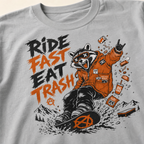 Granite gray t-shirt with a graphic of a raccoon on a skateboard and text 'Ride Fast Eat Trash' on a beige background.