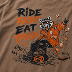 T-shirt with a raccoon graphic and text 'Ride Fast Eat Trash' on a brown background