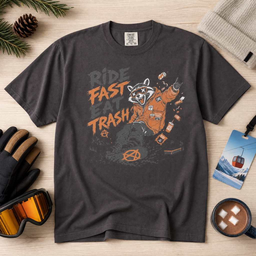 Graphite gray t-shirt with graphic design and text on a wooden surface with accessories.