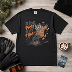 Black t-shirt with graphic design and text on a wooden surface with accessories.