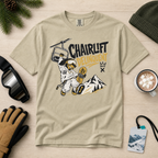 Khaki colored t-shirt with a snowboarding graphic and 'Chairlift Delinquent' text on a wooden surface with winter accessories.
