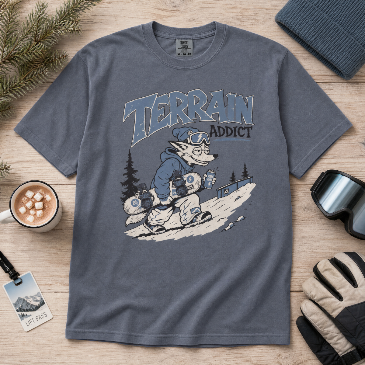 Denim gray t-shirt with 'Terrain Addict' graphic on a wooden surface with winter accessories.