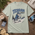 Bay green t-shirt with 'Terrain Addict' graphic on a wooden surface with winter accessories.