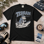 Black t-shirt with 'Terrain Addict' graphic on a wooden surface with winter accessories.