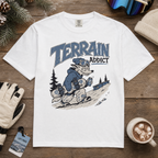White t-shirt with 'Terrain Addict' graphic on a wooden surface with winter accessories.