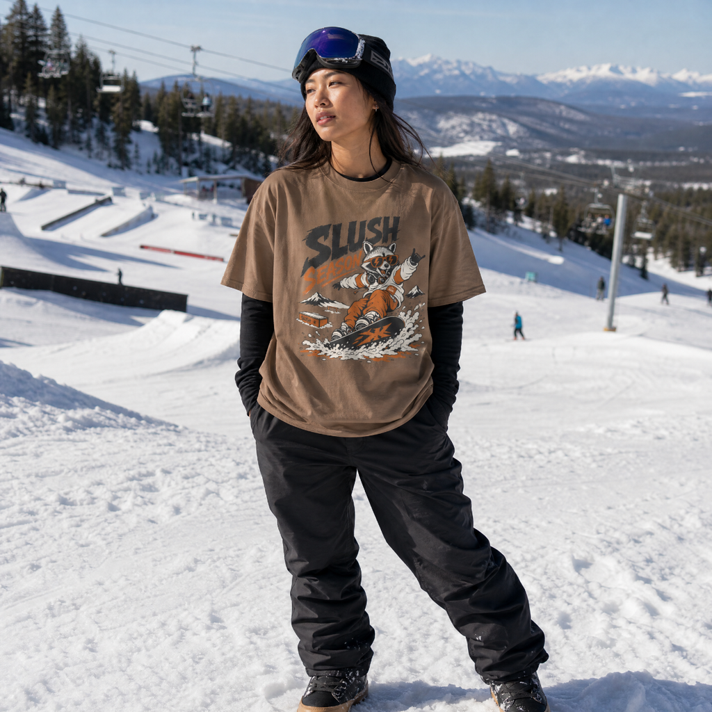 Person wearing a 'Slush' t-shirt on a snowy slope with mountains in the background