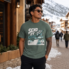 Man wearing a blue spruce green t-shirt with a graphic design in a snowy town setting