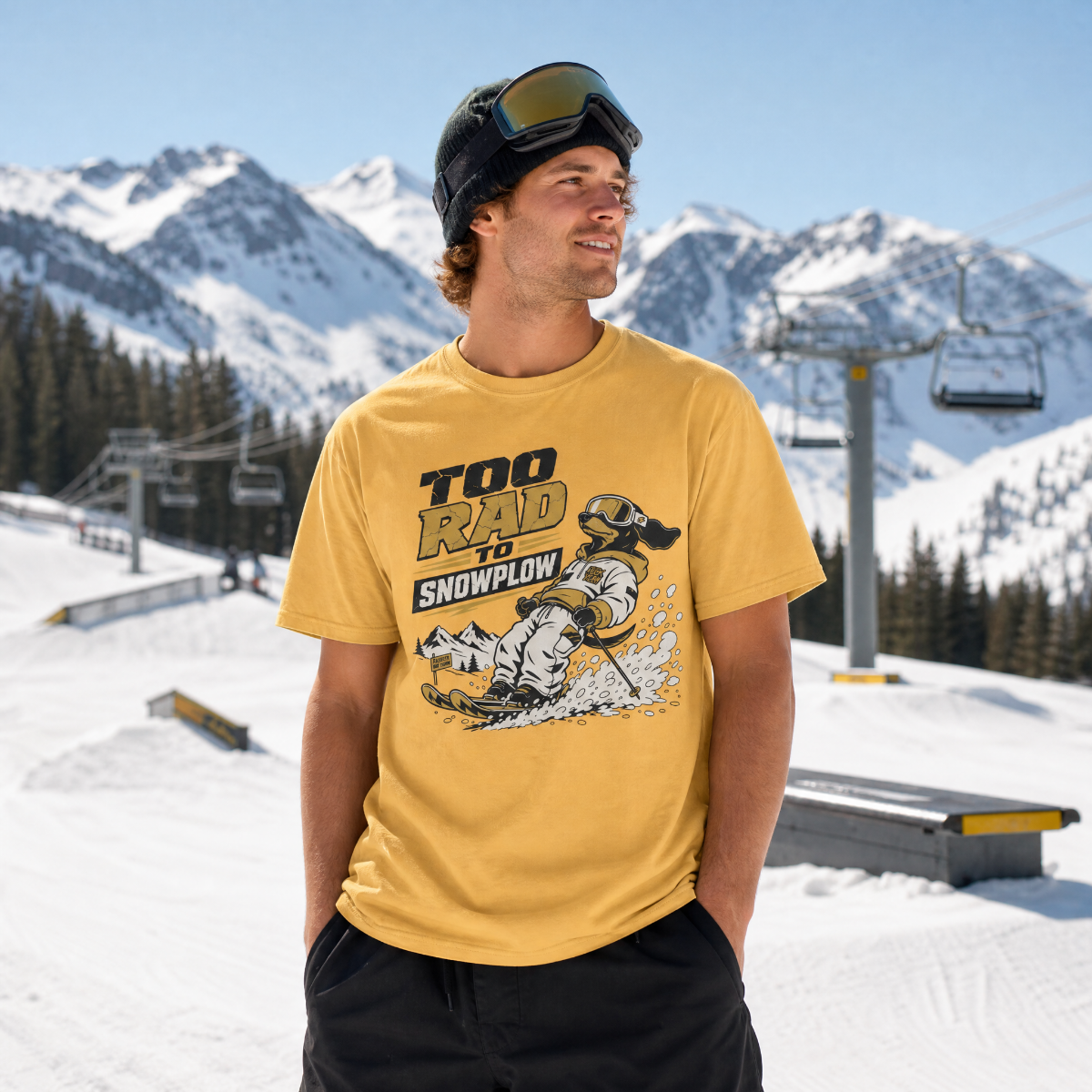Man wearing a yellow t-shirt with a snowplow graphic and text in a snowy mountain setting.
