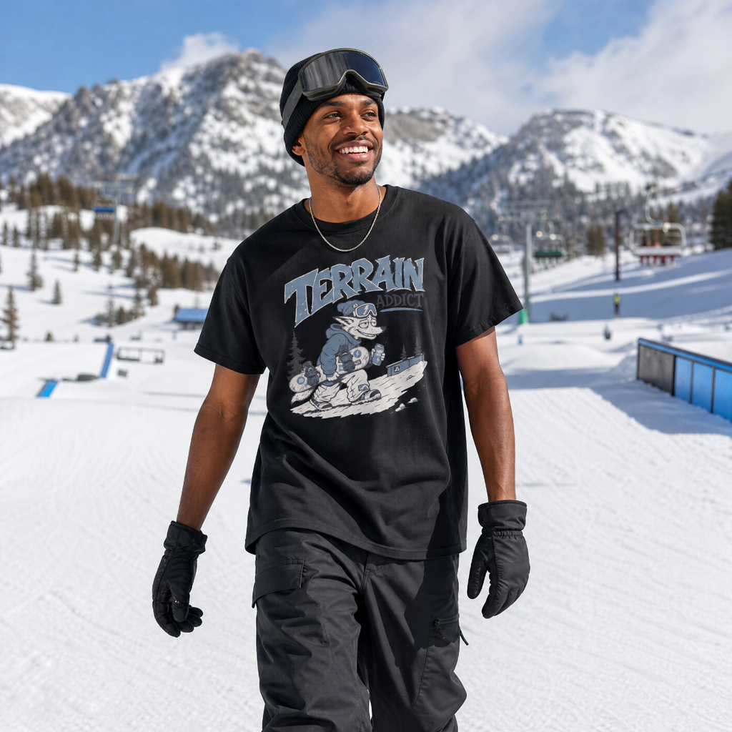 Person wearing a black t-shirt with 'Terrain Addict' graphic in a snowy mountain setting