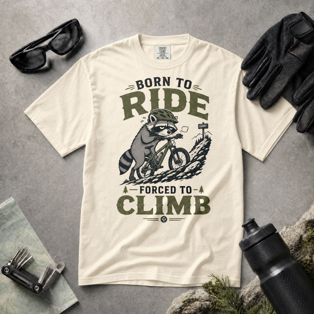 Ivory white t-shirt with a graphic of a raccoon riding a bike and text 'Born to Ride, Forced to Climb'.