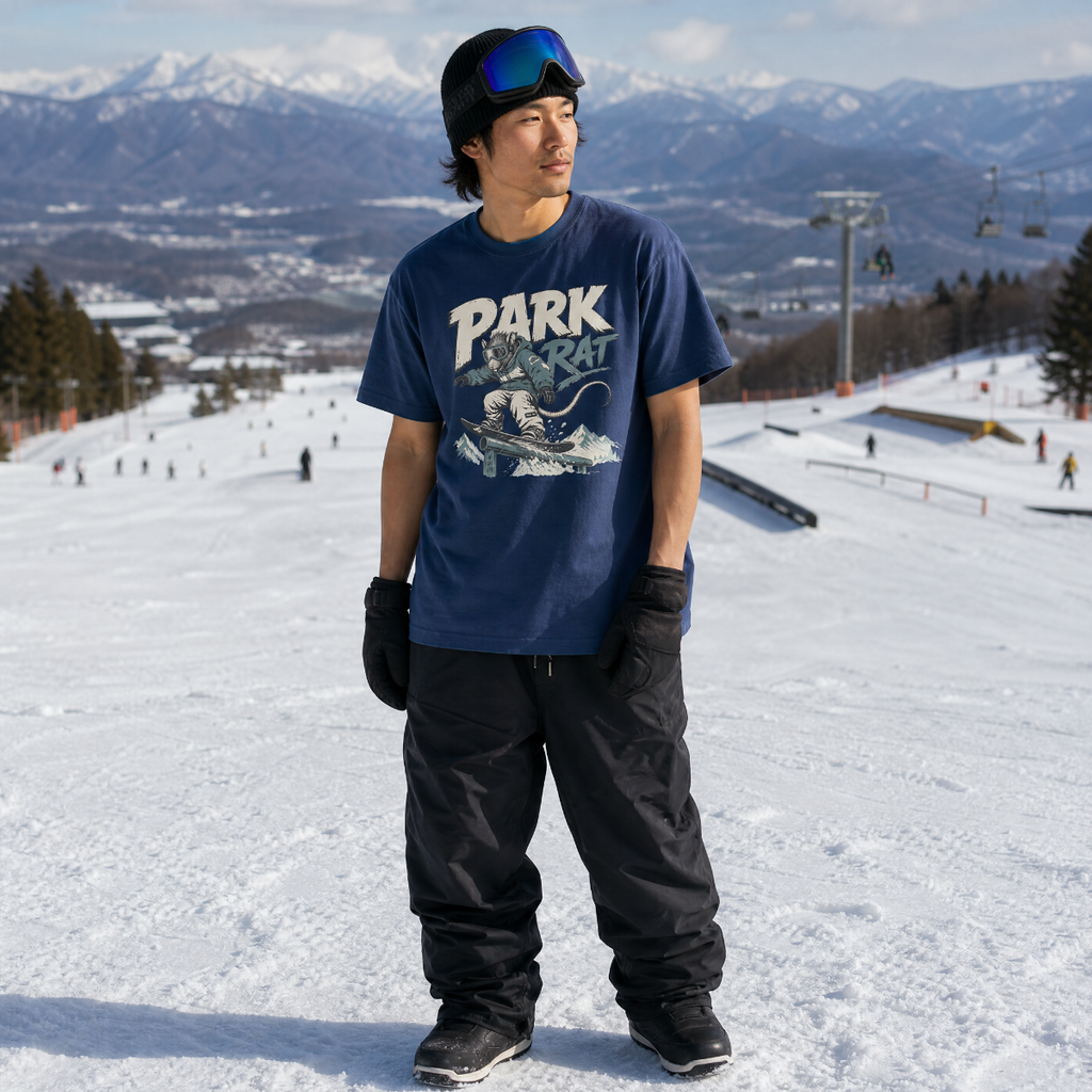 Person wearing a 'Park Rat' t-shirt on a snowy slope with mountains in the background