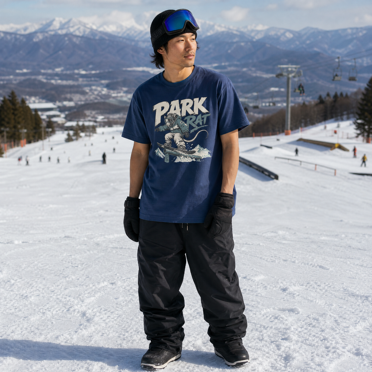 Person wearing a 'Park Rat' t-shirt on a snowy slope with mountains in the background