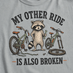 T-shirt with a raccoon and bicycles graphic and text on a gray background