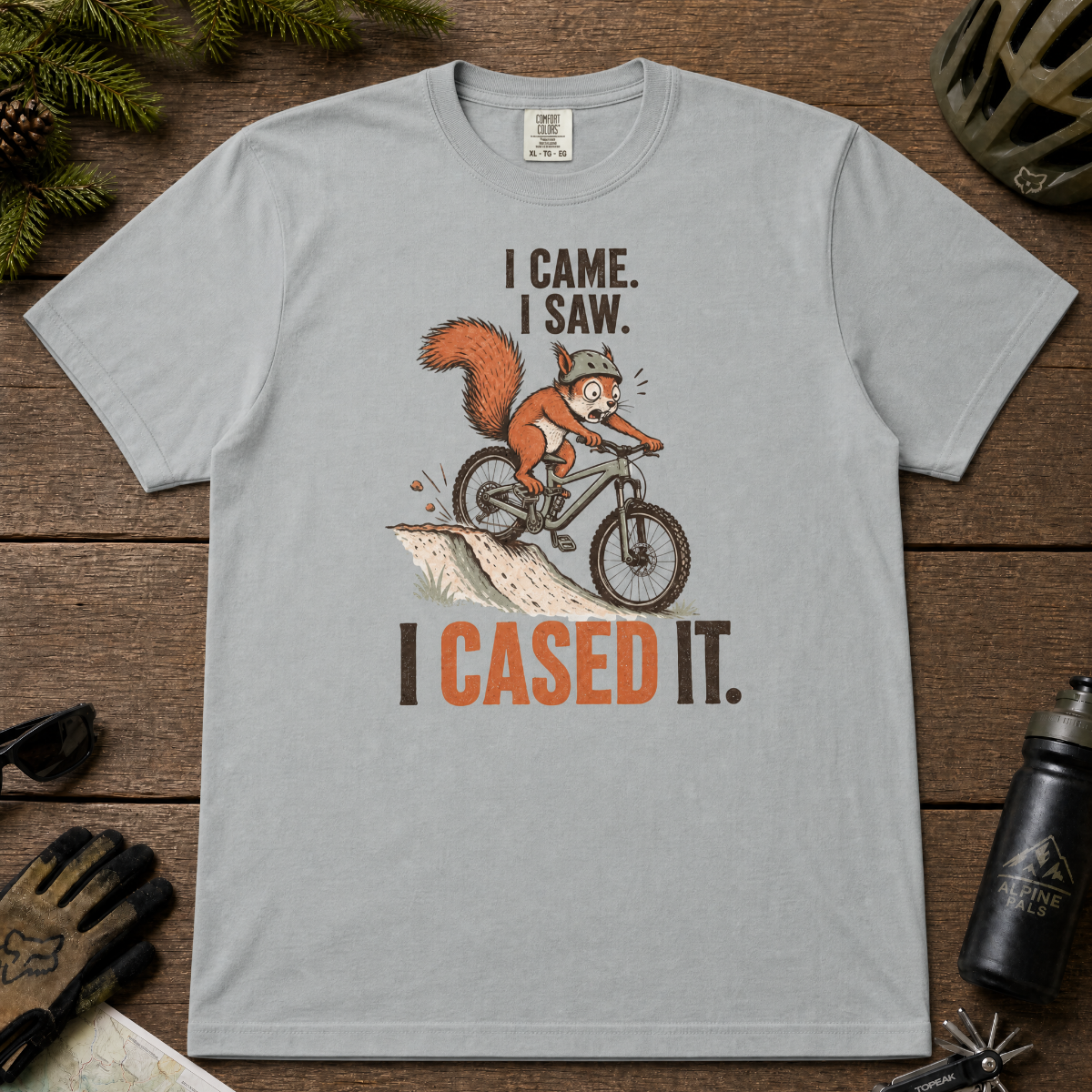 Granite gray t-shirt with a graphic of a squirrel on a bike and text 'I Came. I Saw. I Cased It.' on a wooden surface.