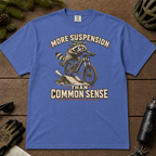 Mystic blue t-shirt with a raccoon riding a bike graphic and text 'More suspension than common sense'.