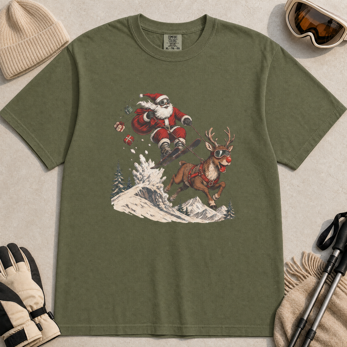 Hemp green t-shirt with Santa Claus and reindeer graphic on a light beige surface with winter accessories.