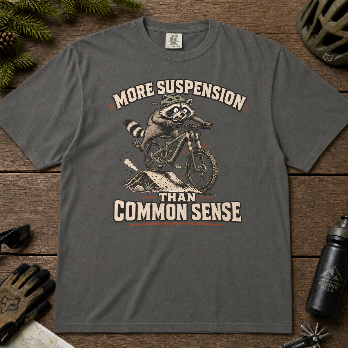 Pepper gray t-shirt with a raccoon riding a bike graphic and text 'More suspension than common sense'.