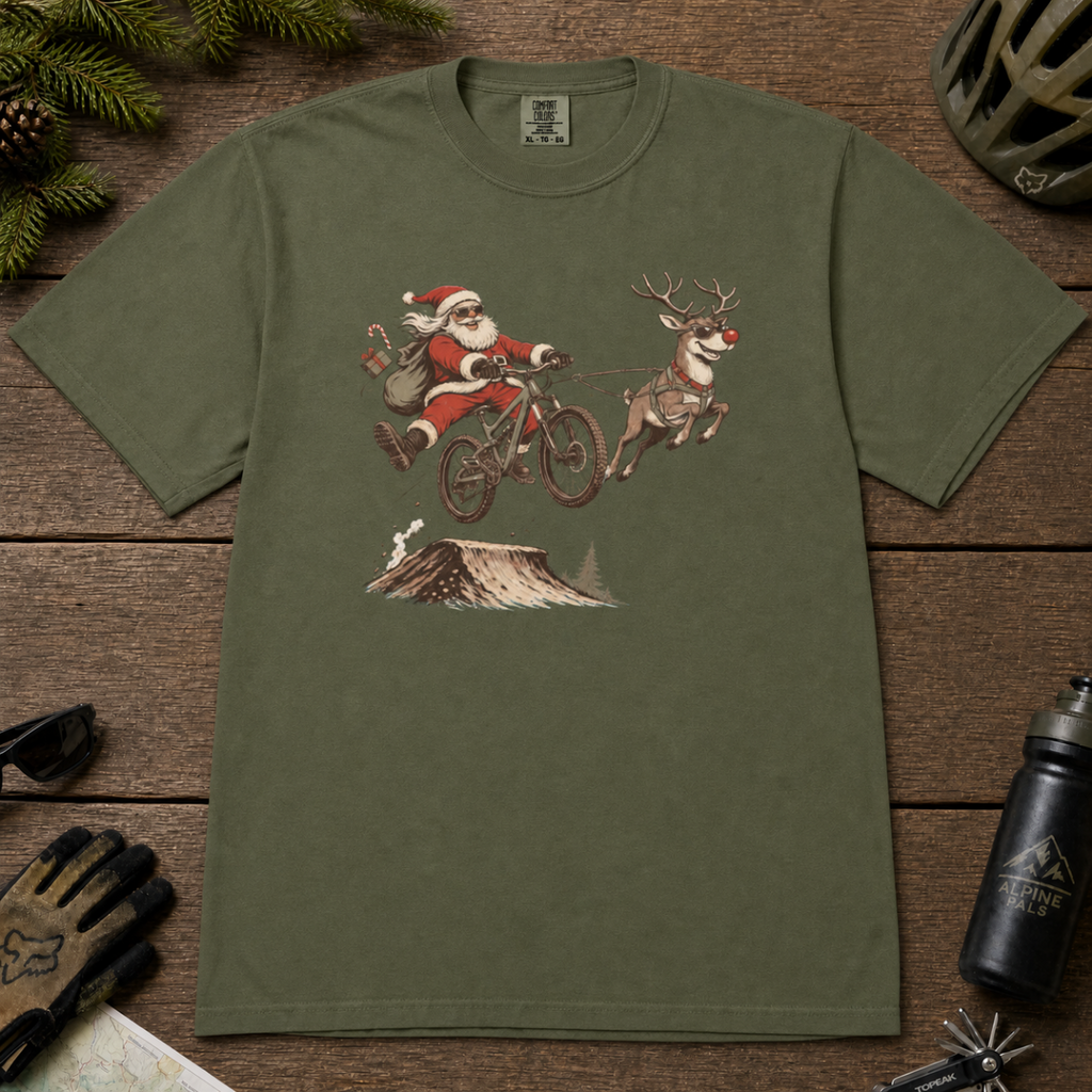 Hemp green t-shirt with Santa Claus riding a bike and reindeer design on a wooden surface.