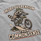 Granite gray t-shirt with a raccoon riding a bike graphic and text 'More suspension than common sense'.