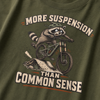 Hemp green t-shirt with a raccoon riding a bike graphic and text 'More suspension than common sense'.