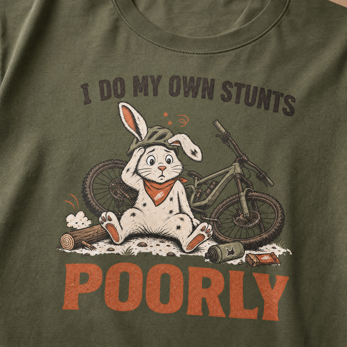 Hemp green t-shirt with a graphic of a rabbit and bicycle and text 'I do my own stunts poorly' on a plain background.