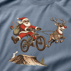 T-shirt with a graphic of Santa Claus riding a bike with a reindeer, on a blue background.