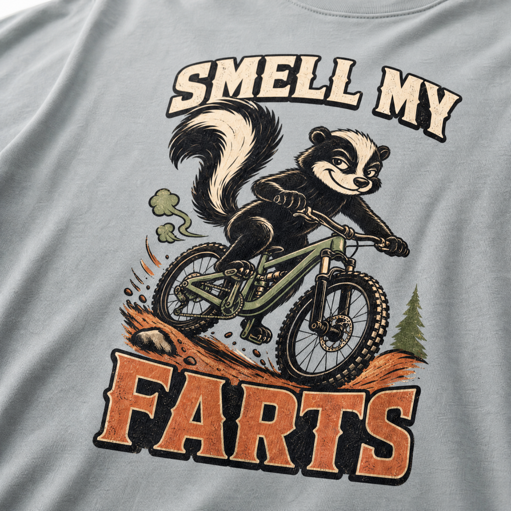 Granite gray t-shirt with a graphic of a raccoon riding a bike and text 'Smell my Farts'.