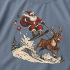 T-shirt with a graphic of Santa Claus skiing with a reindeer on a blue jean colored background
