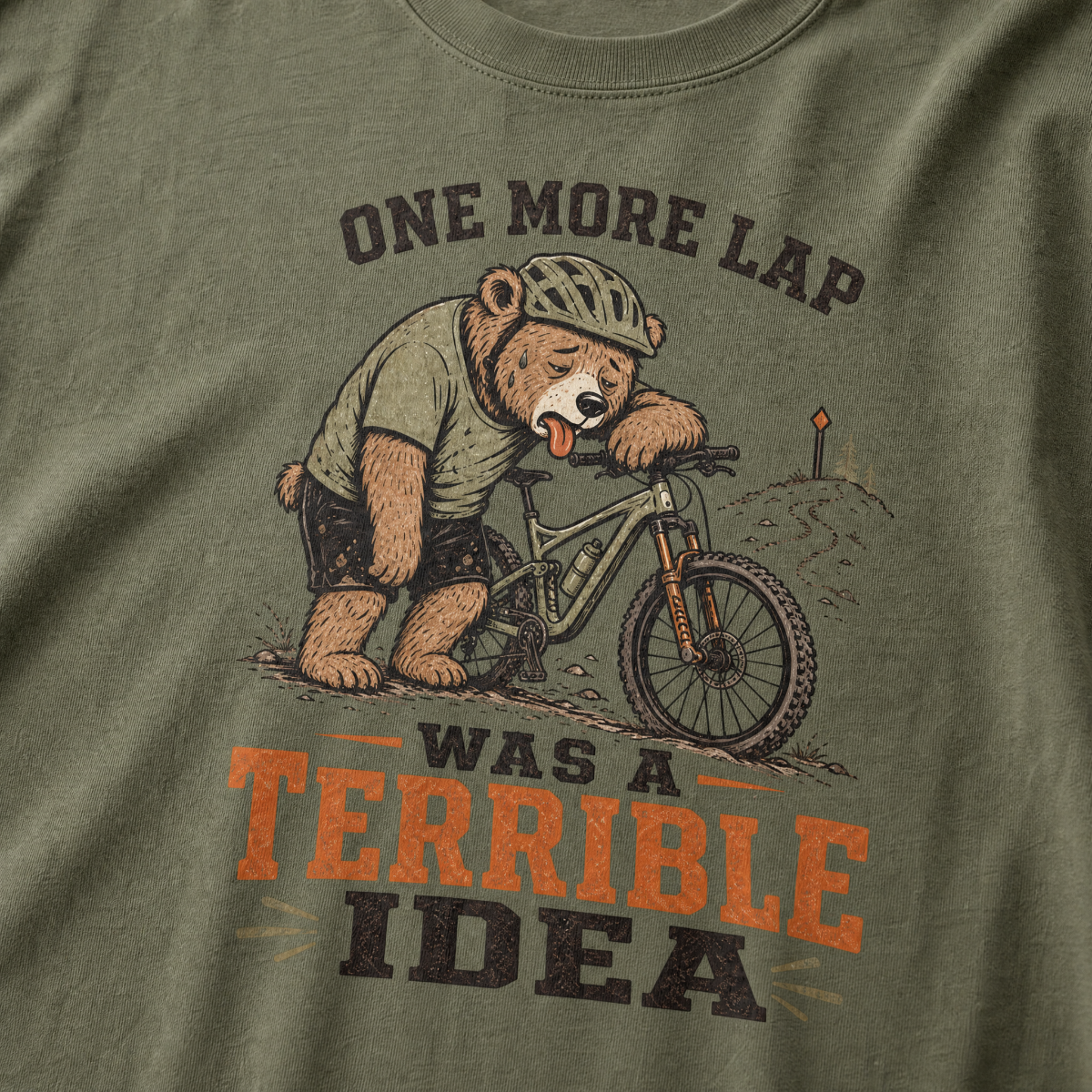 Moss green t-shirt with a bear riding a bike graphic and text 'One more lap was a terrible idea'.