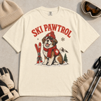 Ivory white t-shirt with a dog graphic and 'Ski Pawtrol' text, surrounded by winter accessories on a light background.
