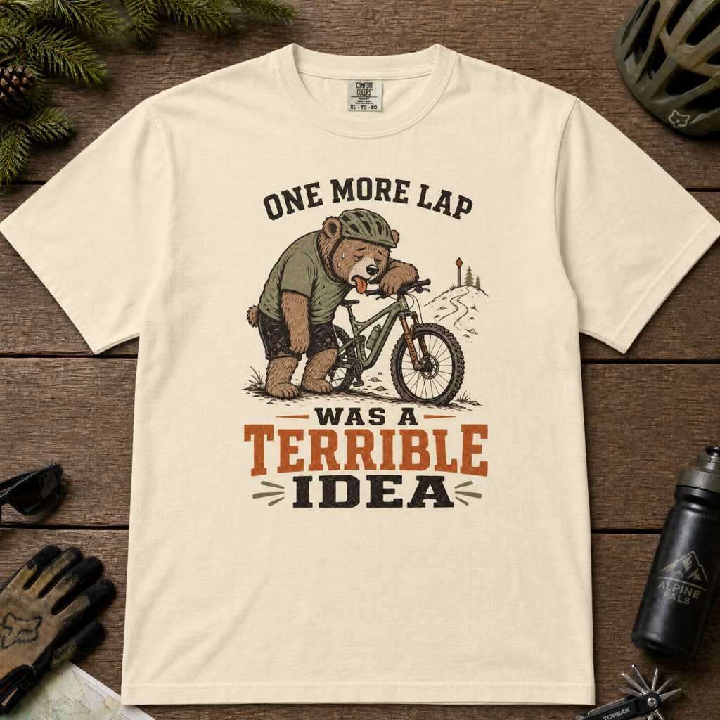 Ivory white t-shirt with bear graphic and text on a wooden surface with cycling accessories.