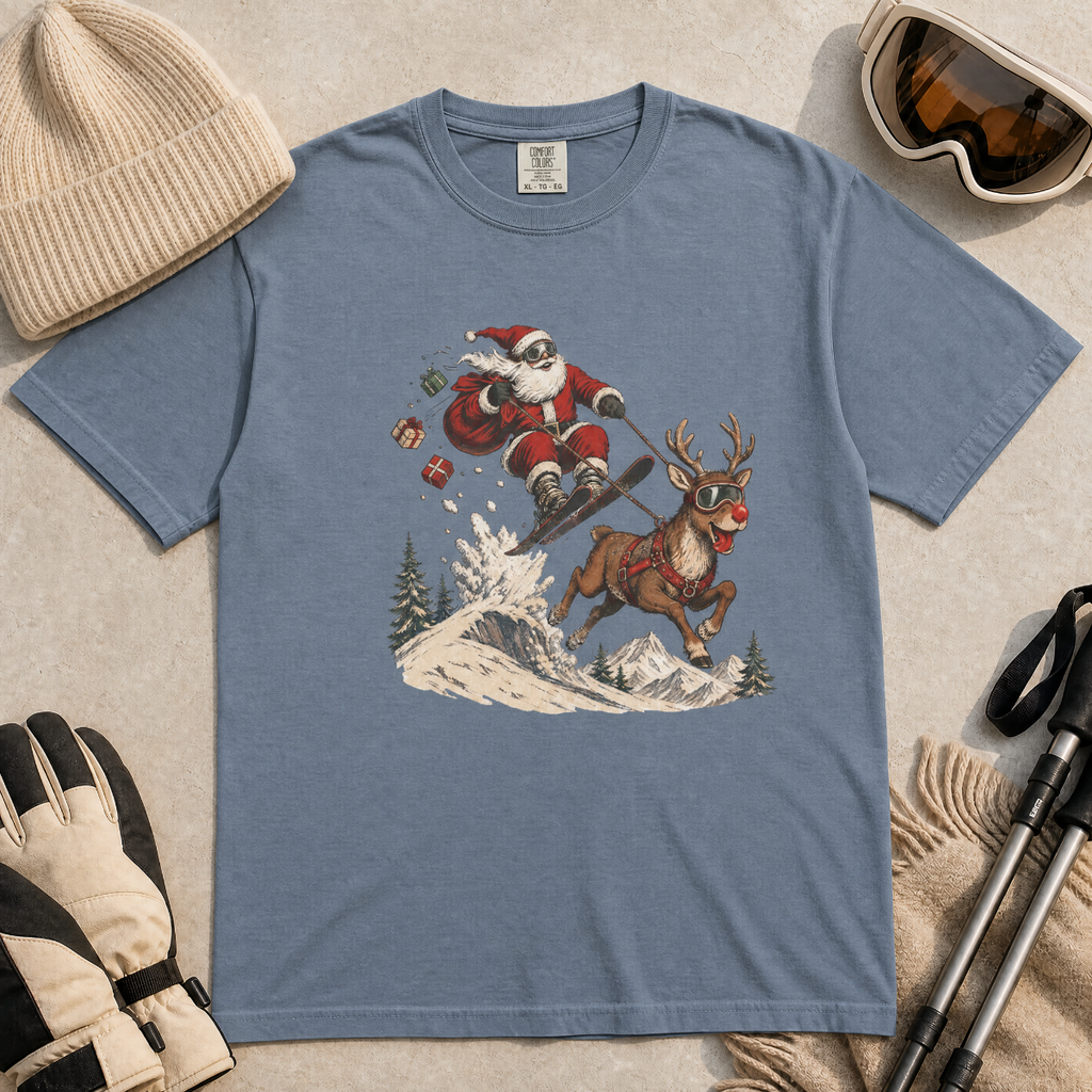 Blue jean colored t-shirt with Santa Claus and reindeer graphic, surrounded by winter accessories on a beige surface.