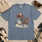 Blue jean colored t-shirt with Santa Claus and reindeer graphic, surrounded by winter accessories on a beige surface.