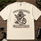Ivory white t-shirt with a raccoon riding a bike graphic and text 'More suspension than common sense'.