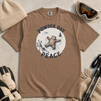 Flat lay of an espresso brown t-shirt featuring a peaceful bear snow angel ski graphic with “Powder Day Peace” text, styled with winter accessories.
