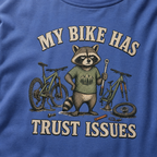 Mystic blue t-shirt with a raccoon graphic and text 'My bike has trust issues' on a blue background