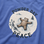 Close-up of a mystic blue t-shirt with a vintage ski design showing a relaxed bear making a snow angel beside skis, with “Powder Day Peace” text.