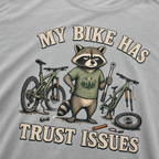 Granite gray t-shirt with a raccoon graphic and text 'My bike has trust issues' on a bicycle-themed design.