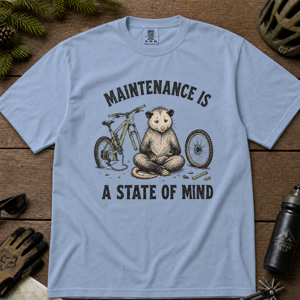 Washed denim blue t-shirt featuring a possum meditating while fixing a bike with text, "Maintenance is a State of Mind".
