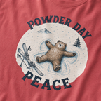 Close-up of a crimson red t-shirt with a vintage ski design showing a relaxed bear making a snow angel beside skis, with “Powder Day Peace” text.