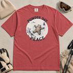 Flat lay of a crimson red t-shirt featuring a peaceful bear snow angel ski graphic with “Powder Day Peace” text, styled with winter accessories.