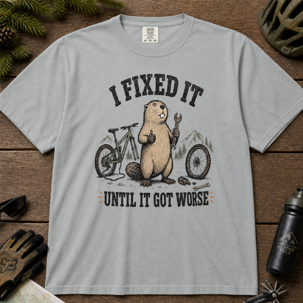 Graphite gray t-shirt with beaver graphic and text on a wooden surface with bike-related items.