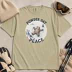 Flat lay of a bay green t-shirt featuring a peaceful bear snow angel ski graphic with “Powder Day Peace” text, styled with winter accessories.