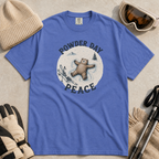 Flat lay of a mystic blue t-shirt featuring a peaceful bear snow angel ski graphic with “Powder Day Peace” text, styled with winter accessories.