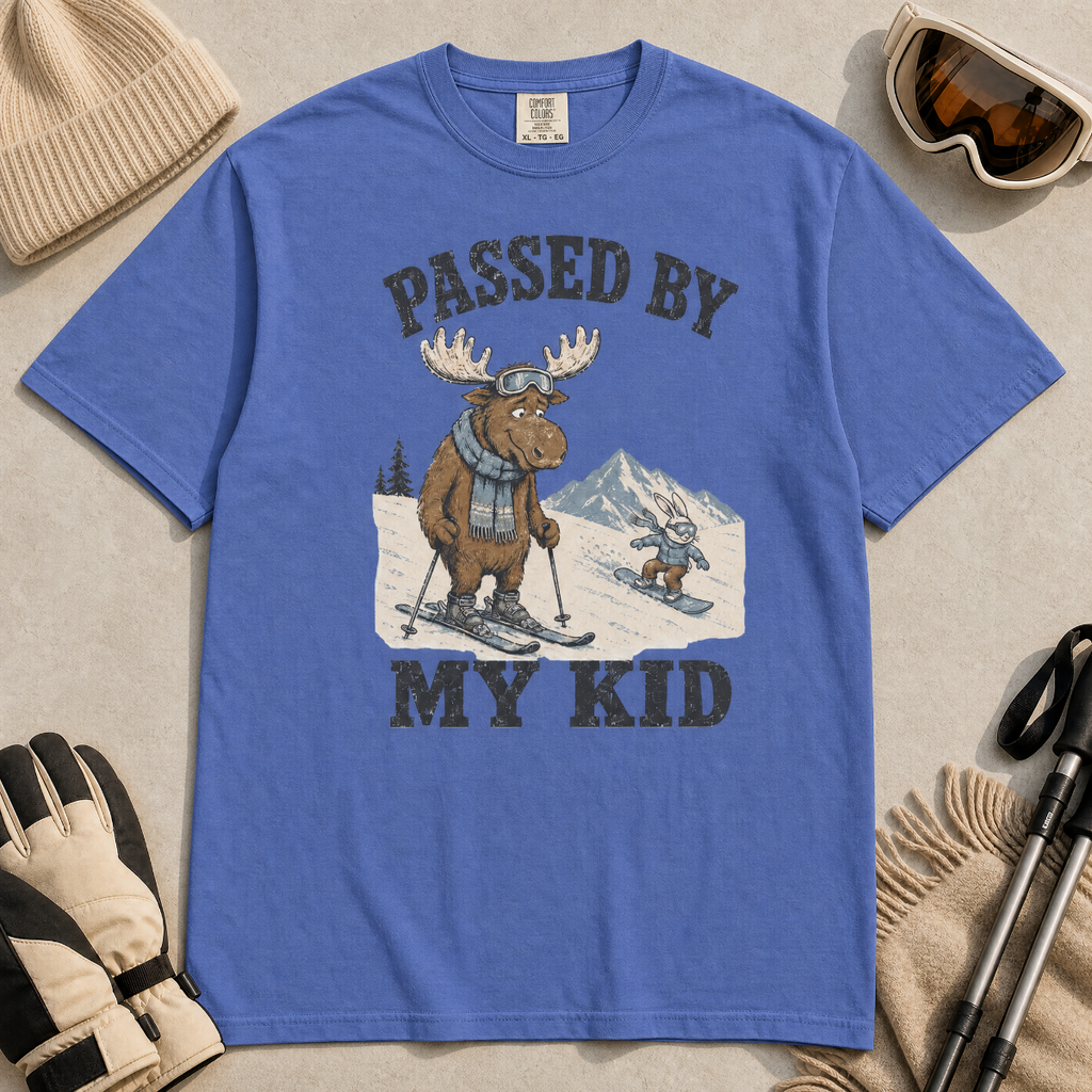 Flat lay of a mystic blue t-shirt featuring a funny “Passed By My Kid” ski design with a humbled moose watching a small rabbit snowboarder pass by.