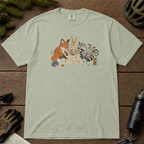 Flat lay of a bay green t-shirt featuring a cute woodland animal trail-planning graphic with a fox, rabbit, raccoon, map, helmet, bike, and trail marker.