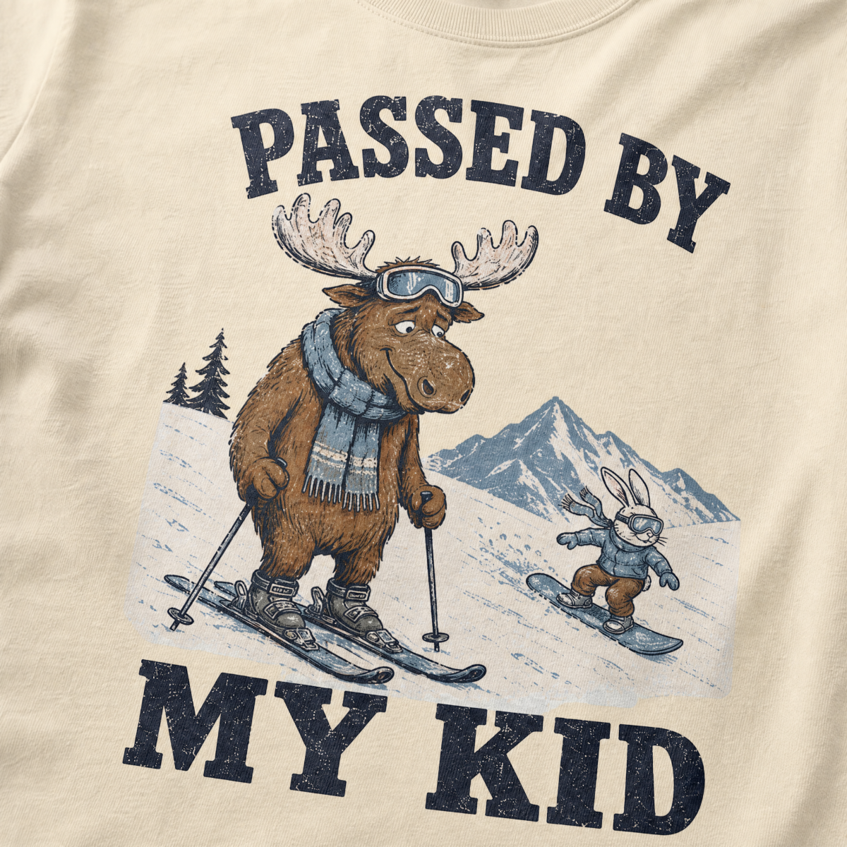 Close-up of a ivory white t-shirt with a vintage “Passed By My Kid” design showing an embarrassed moose skier being passed by a tiny rabbit snowboarder.