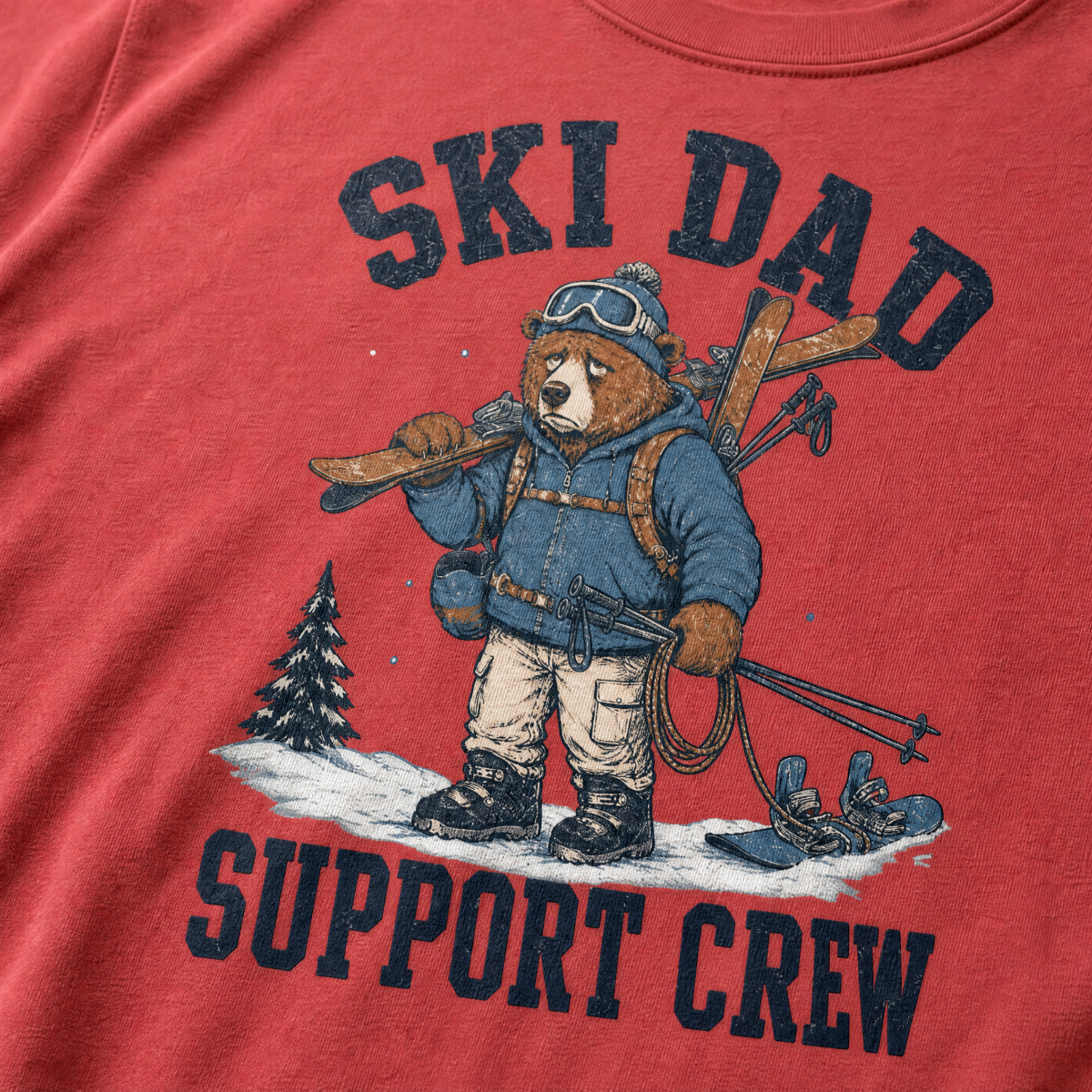 Close-up of a crimson red t-shirt with a vintage ski dad design showing an exhausted bear loaded with skis, poles, and snow gear.