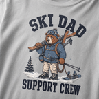 Close-up of a granite gray t-shirt with a vintage ski dad design showing an exhausted bear loaded with skis, poles, and snow gear.