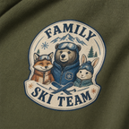 Close-up of a hemp green t-shirt with a retro badge design showing a bear, fox, and rabbit as a “Family Ski Team.”